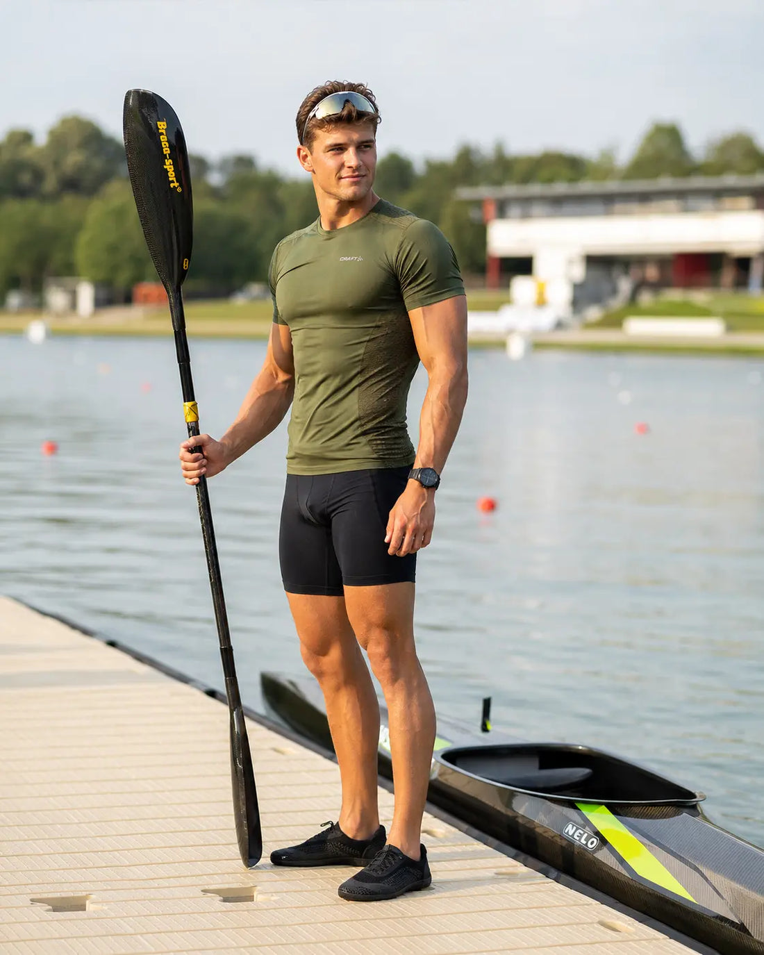 Competitive paddler wearing a performance unisuit and race-day kit at a sprint kayak event