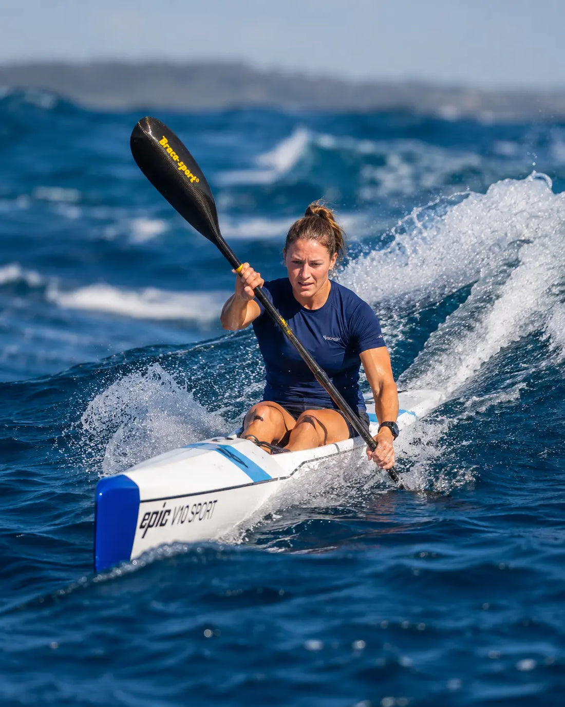 Surfski paddler racing downwind on open ocean swells during a surfski ocean race