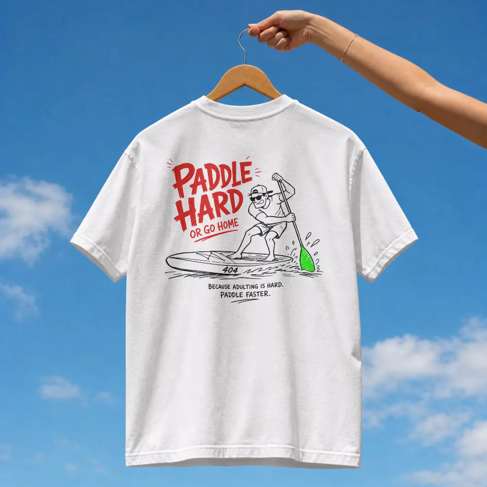 A white short-sleeve graphic T-shirt hanging on a wooden hanger against a blue sky with clouds. A human arm and hand are visible holding the hanger.